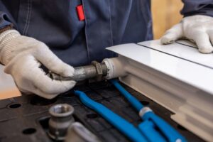 Plumber installs a valve on a radiator during a repair